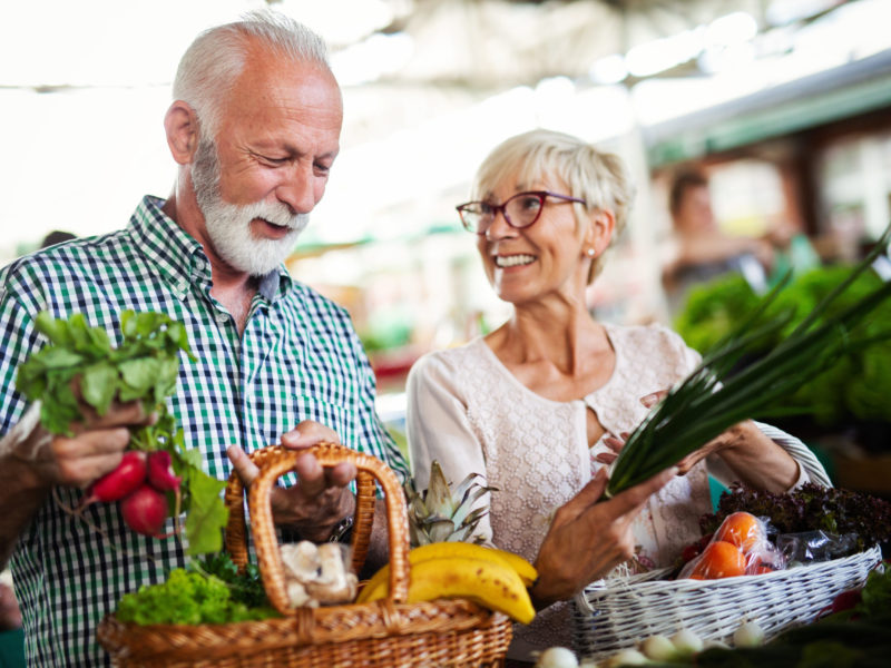 Happy senior couple buying fresh food at the market